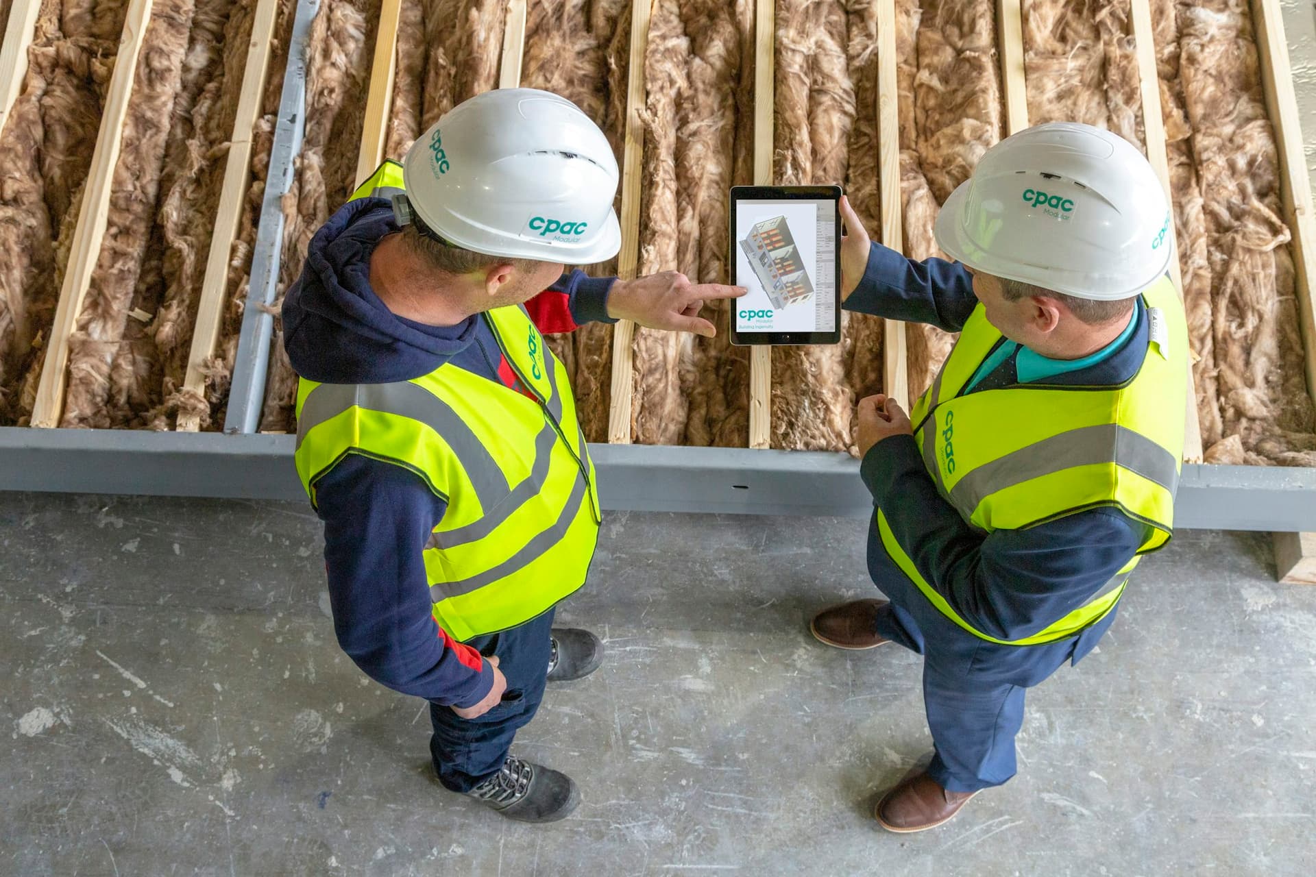 Deux techniciens consultent des plans sur une tablette lors d'une visite