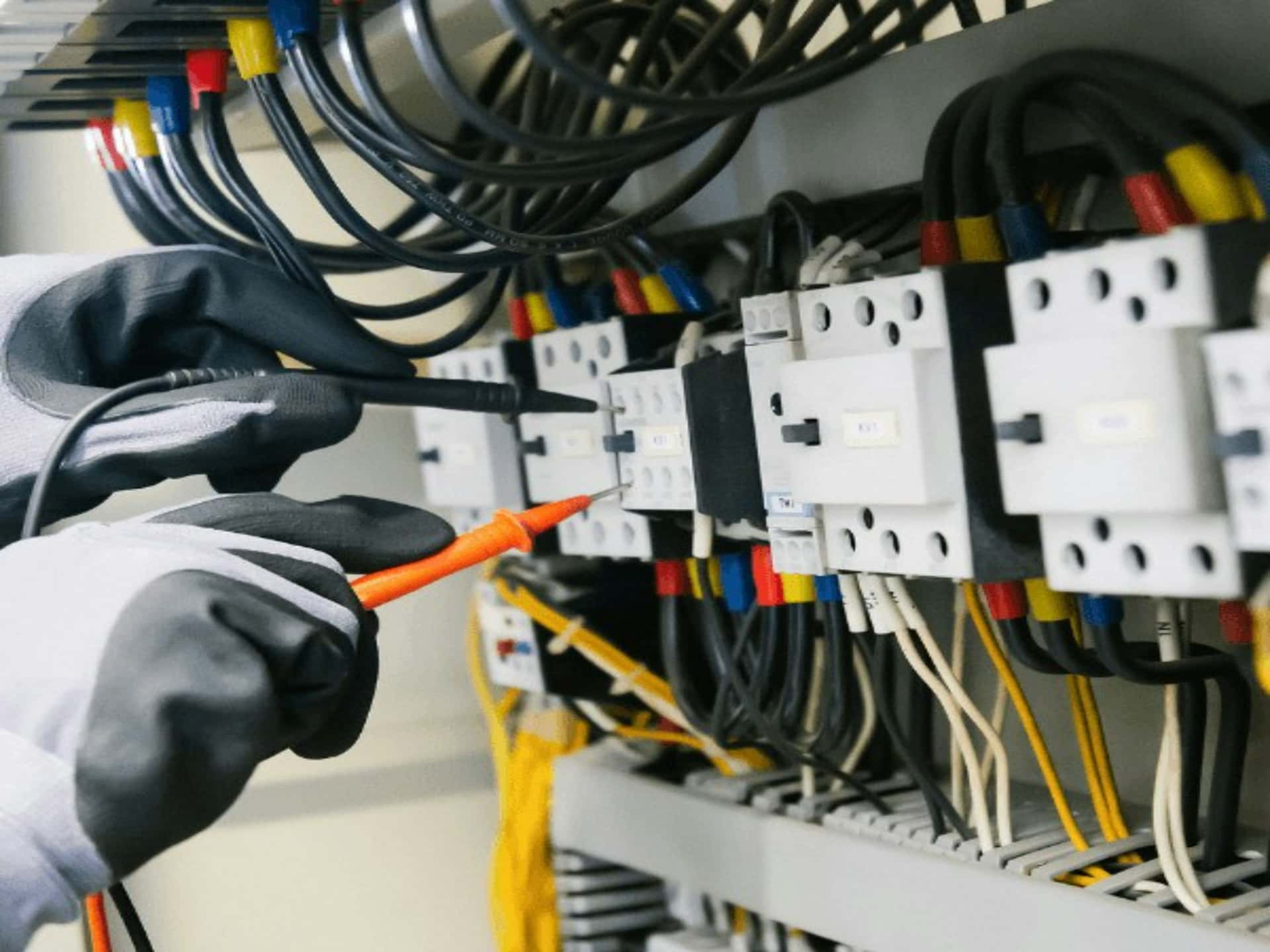 Technicien contrôlant un tableau électrique avec un multimètre lors d'une mise en service